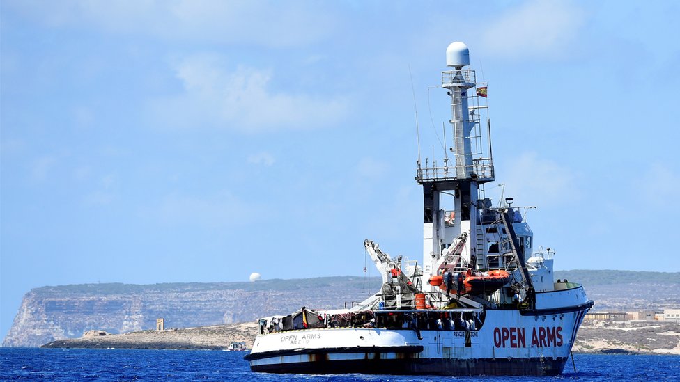 Испанский спасательный корабль для мигрантов Open Arms перед памятником «Дверь в Европу», недалеко от итальянского берега в Лампедузе