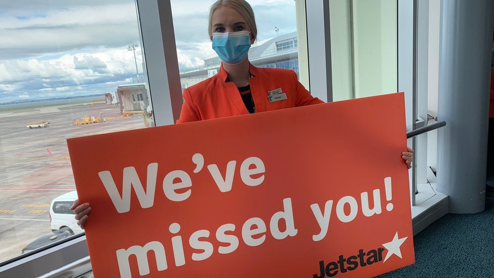 Jetstar crew worker holds sign saying we've missed you