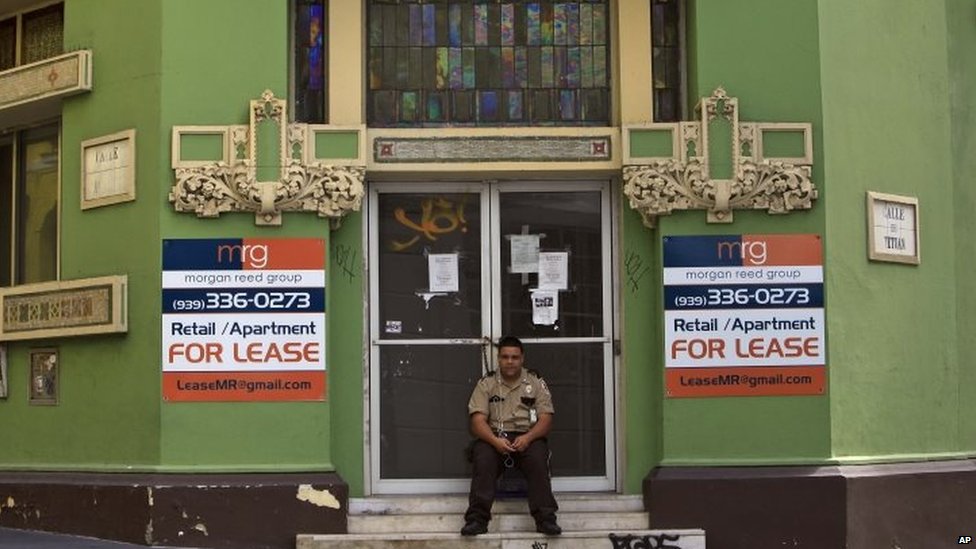 Частный охранник сидит перед закрытым бизнесом в колониальном районе Олд Сан-Хуан, Пуэрто-Рико (2 августа 2015 г.)