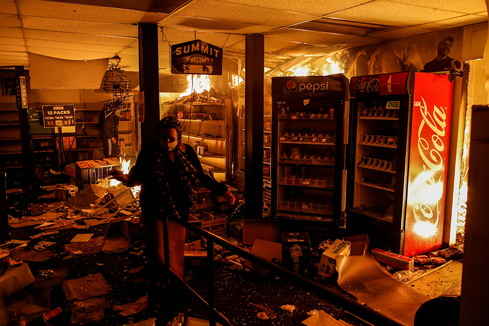 A woman reacts while protesters set fire in a liquor store