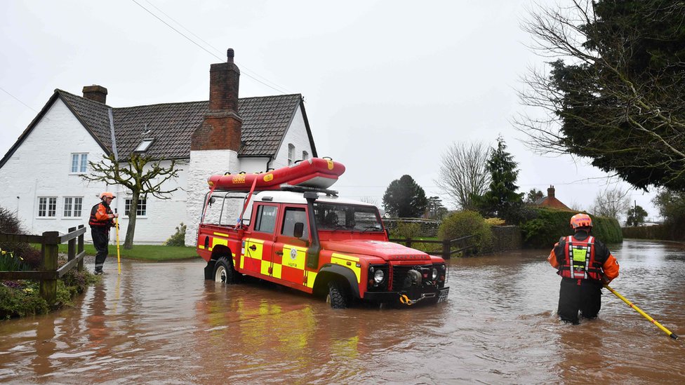 Сотрудники пожарно-спасательной службы Херефорда меняют направление своего автомобиля, поскольку вода становится слишком глубокой из-за наводнения в деревне Хэмптон-Бишоп в Херефордшире, западная Англия