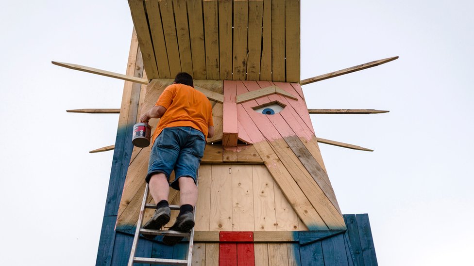 People work on a wooden statue made to resemble US President Donald Trump in the village of Sela pri Kamniku in August 2019