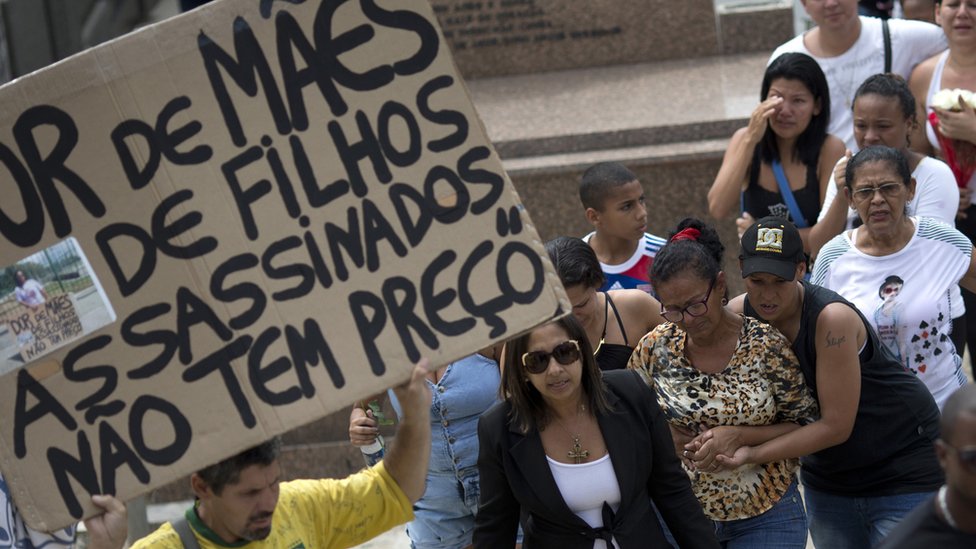 Мужчина держит табличку с надписью «Печаль матерей убитых детей не имеет цены» на похоронах Эдуардо Виктора. 30 сен 2015