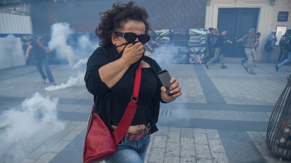 امرأة تحاول تفادي قنابل الغاز
