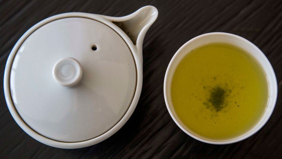 Vasija con té y un pocillo con té verde servido.