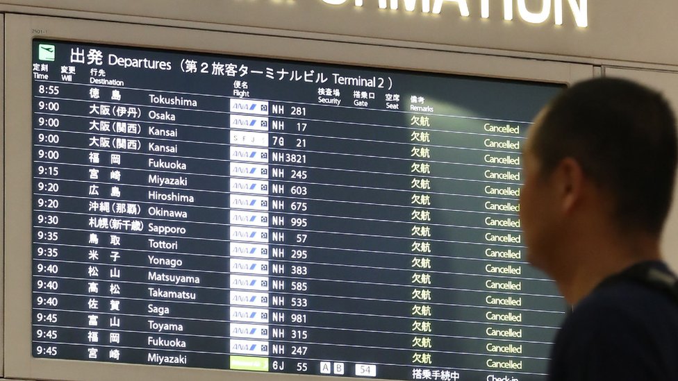 Мужчина смотрит на табло полетной информации в международном аэропорту Ханэда в Токио 12 октября 2019 года.