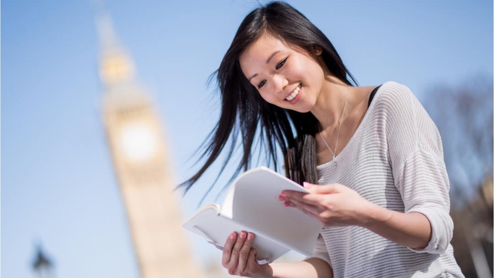 A female student reading in front of the Big Ben in London