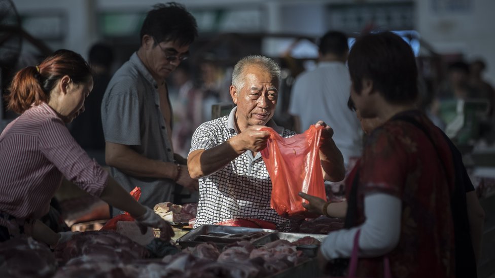 Мясник продает свинину на рынке в Китае