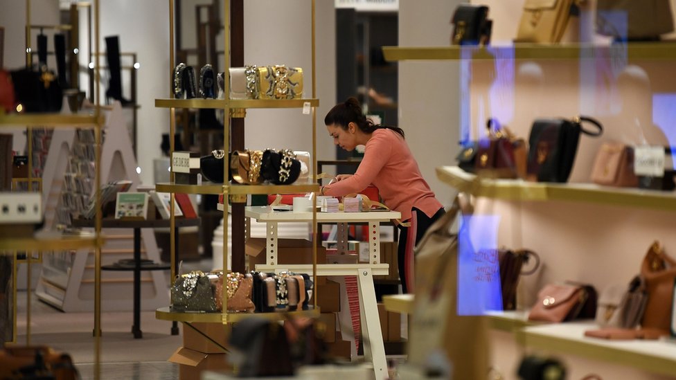 A retail worker prepares a shop to reopen