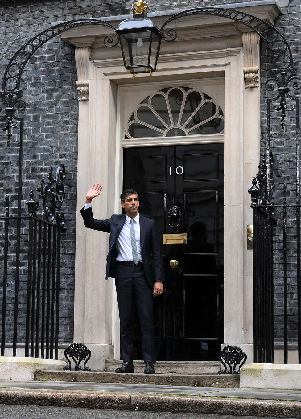 رئيس الوزراء البريطاني المعين حديثاً ريشي سوناك يلوح بيده لدى وقوفه خارج مبنى 10 داوننغ ستريت في وسط لندن في 25 أكتوبر/ تشرين الأول2022