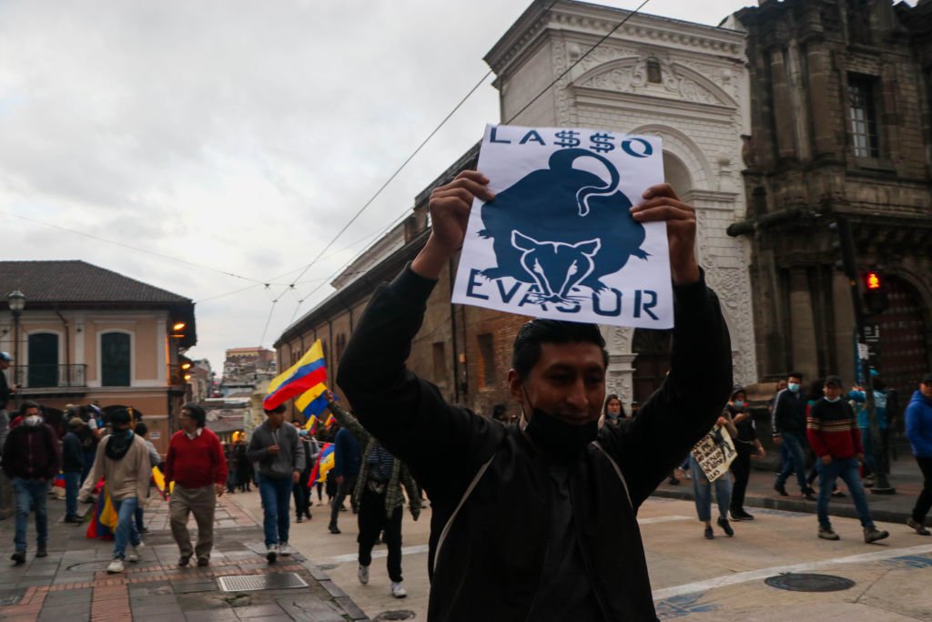 Un hombre sostiene un letrero de protesta contra el presidente Guillermo Lasso.