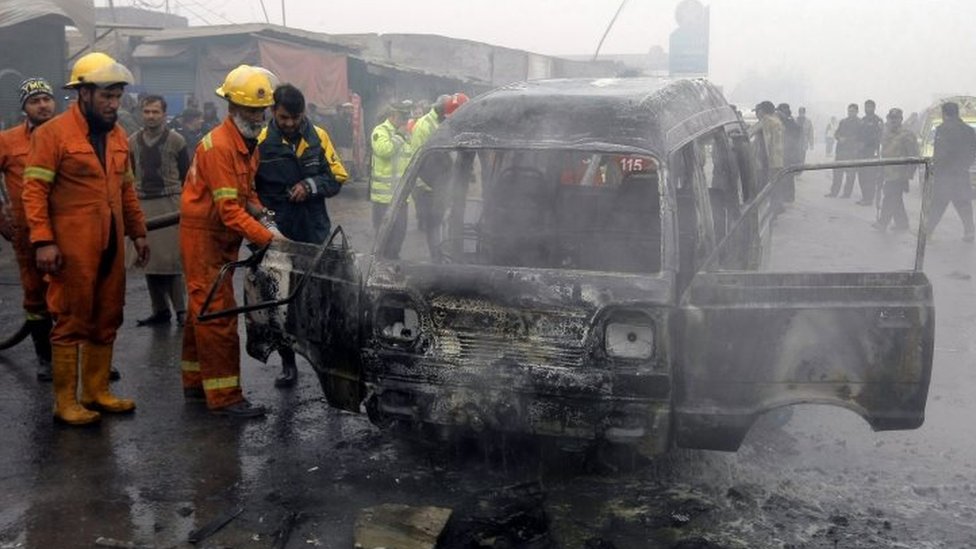 Пакистанские пожарные тушат обломки автомобиля после взрыва бомбы-смертника на окраине Пешавара (19 января 2016 г.)
