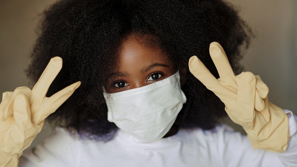 A South African with a mask and gloves showing the signs of victory