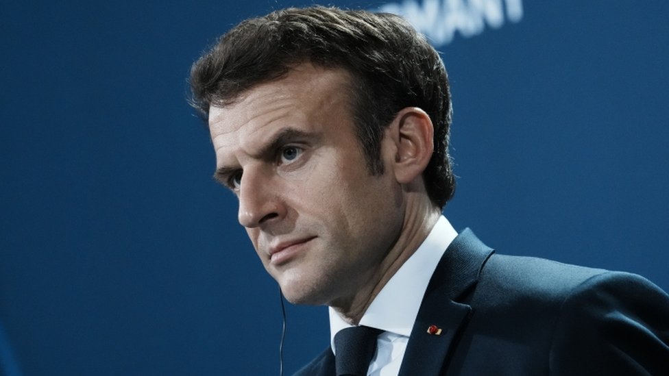Macron de perfil, olhando atentamente para frente em evento