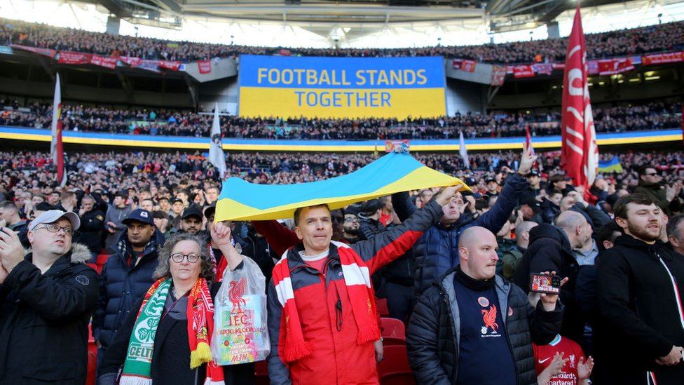 Liverpool fans display a Ukraine flag as the big screen reads 'Football Stands Together' before the Carabao Cup Final match between Chelsea and Liverpool at Wembley Stadium on February 27