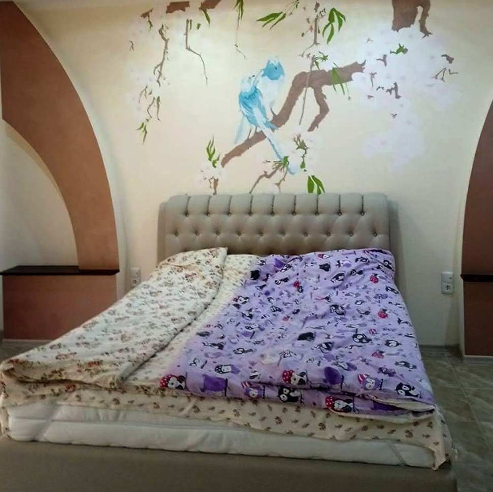 Bedroom with cherry blossom and doves painted on the wall by the bed.