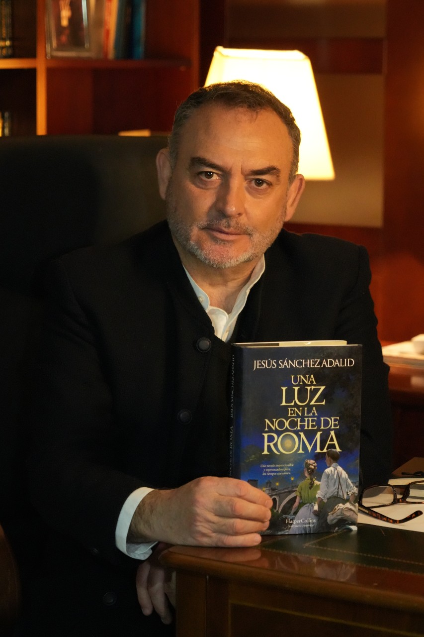 The writer Jesús Sánchez Adalid holds a copy of his novel.
