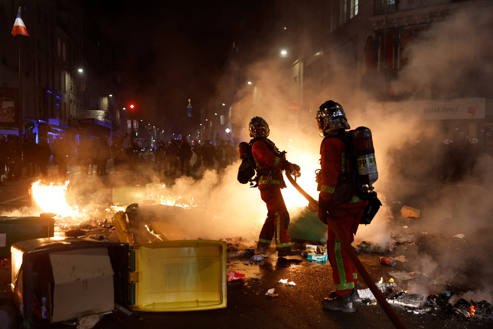 Firefighters extinguish a fire during a demonstration, after the pension reform was adopted as the French Parliament rejected two motions of no-confidence against the government, in Paris, France, March 21, 2023.