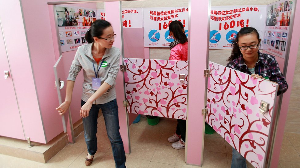 Студентки используют розовые кабинки с писсуарами с табличкой, инструктирующей женщин, как мочиться стоя, в туалете Шаньсиского педагогического университета в Сиане, в провинции Шаньси на северо-западе Китая (26 сентября 2010 г.)