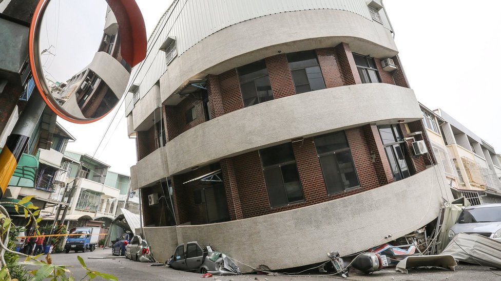 Разбитые машины видны под зданием, которое было повреждено после сильного землетрясения в Тайнане