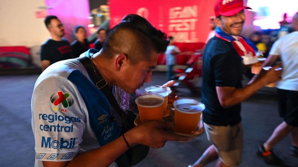 A man sips one of several beers he is carrying