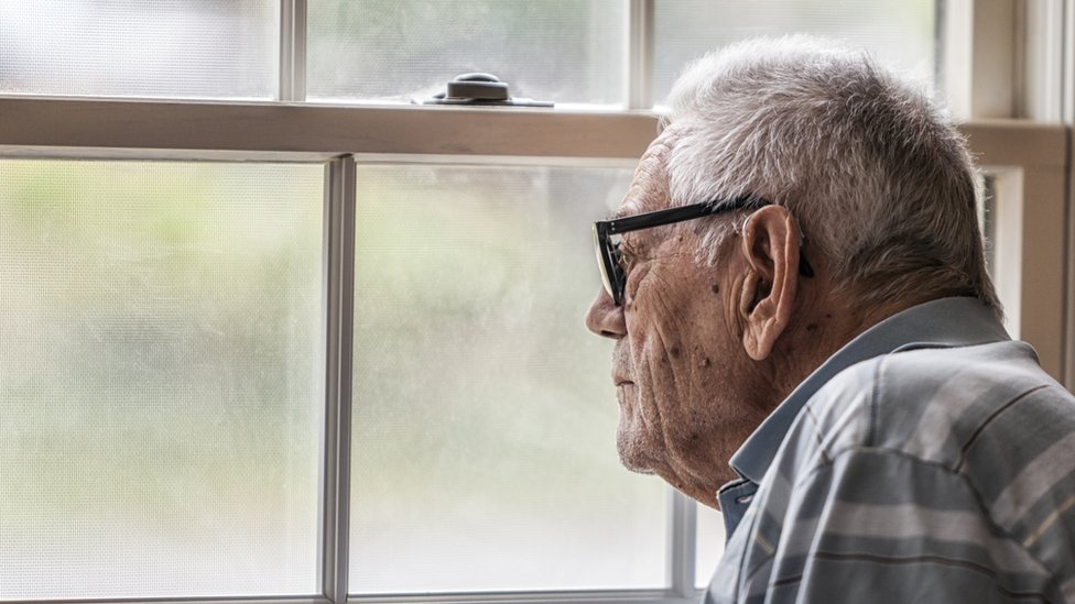 Todavía no se conocen a ciencia cierta las causas del Alzheimer. Anciano mirando a través de una ventana.