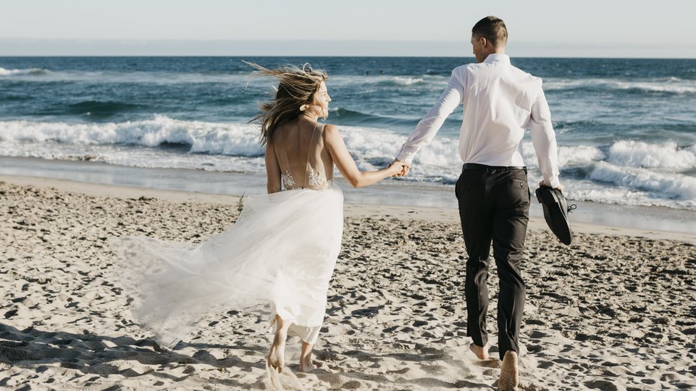 A married couple walking on the beach