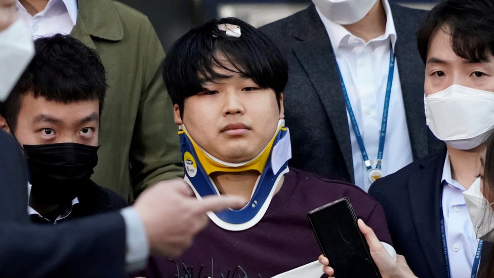 Cho Ju-bin outside the police station, wearing a neck brace