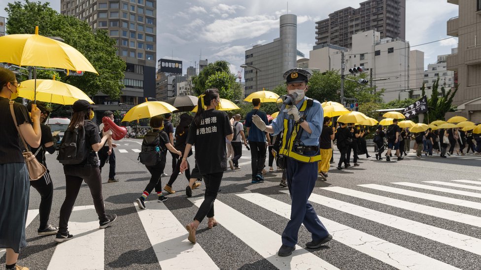 日本東京街頭一名警員為通過馬路的聲援香港示威者維持秩序（12/6/2022）