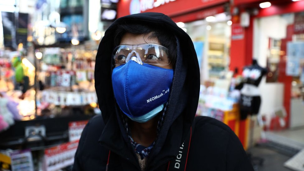 Мужчина в маске во избежание заражения коронавирусом (COVID-19) гуляет по торговому району Мёндон