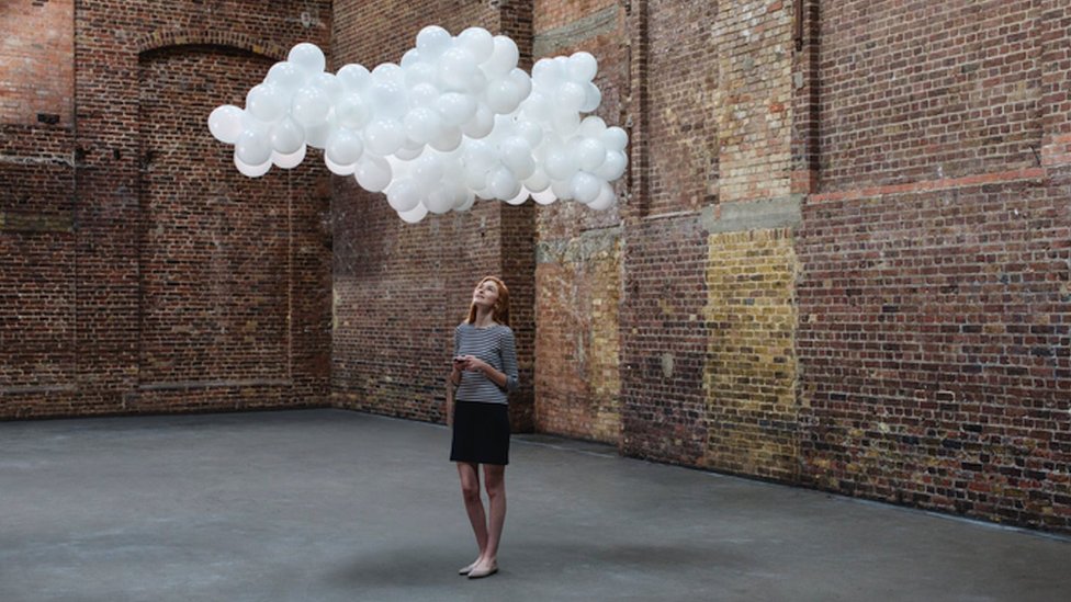 Žena zamišljeno gleda u sintetički oblak iznad glave
