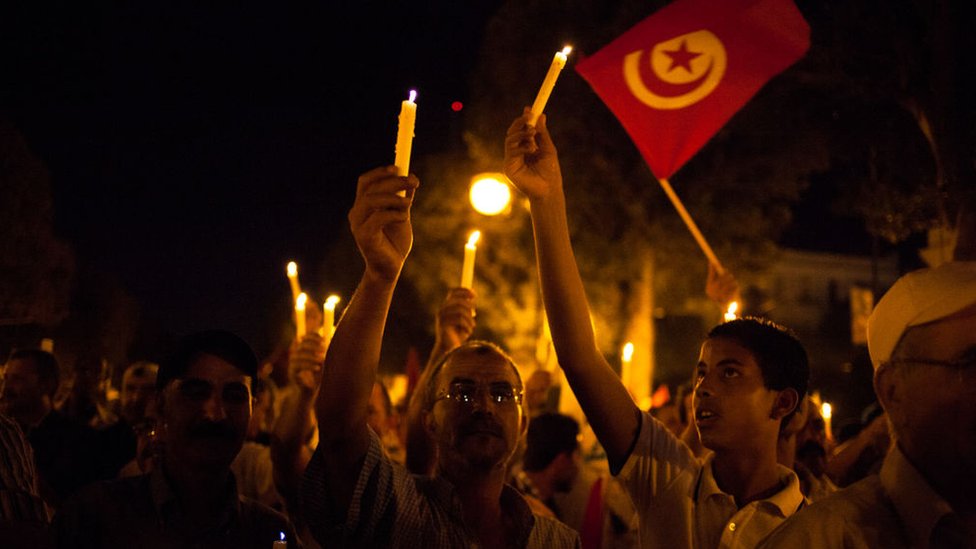 متظاهرون يحملون الشموع والعلم التونسي (أرشيفية)