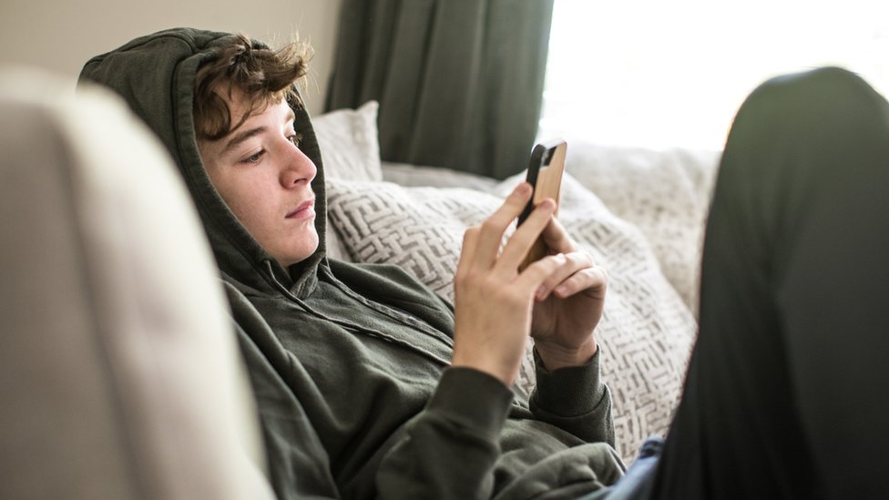 Un adolescente consultando su teléfono móvil