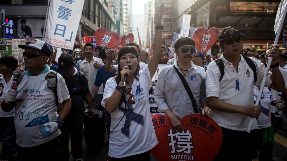 Члены проправительственной группы Blue Ribbon маршируют по улицам Монг Кока в знак протеста против бездействия полиции против демократических активистов 12 октября 2014 года в Гонконге