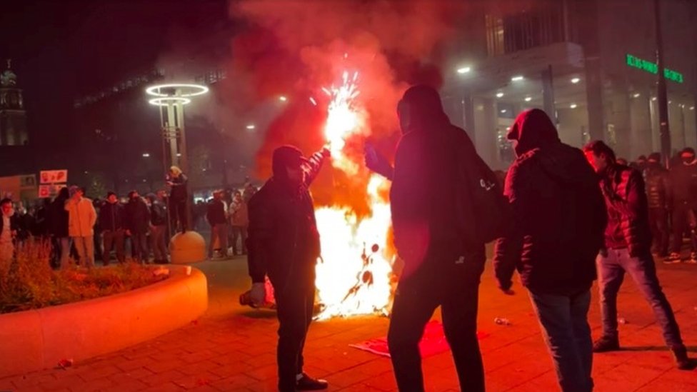 Protesters by a burning motorcycle in Rotterdam