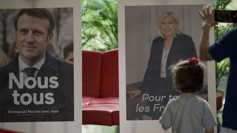Pictures of candidates Emmanuel Macron (L) and Marine Le Pen are displayed during the second round of voting in the French presidential elections at the French Embassy in Beijing on April 24