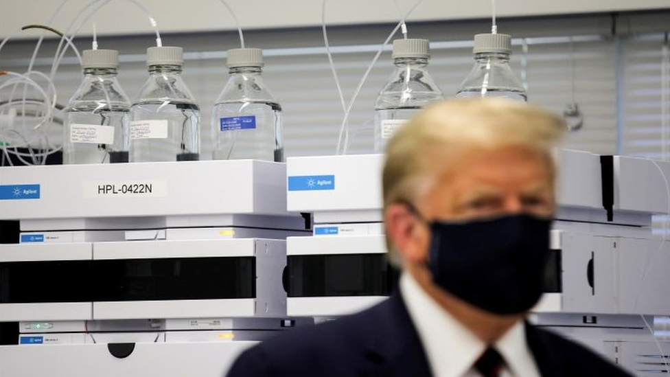 Trump de máscara em laboratório, olhando para o lado