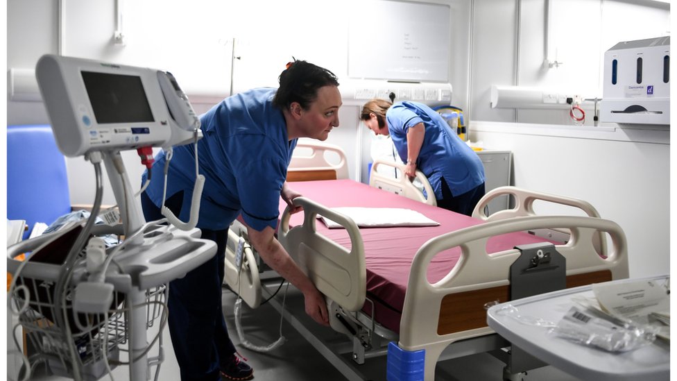 Enfermeiras preparam cama hospitalar