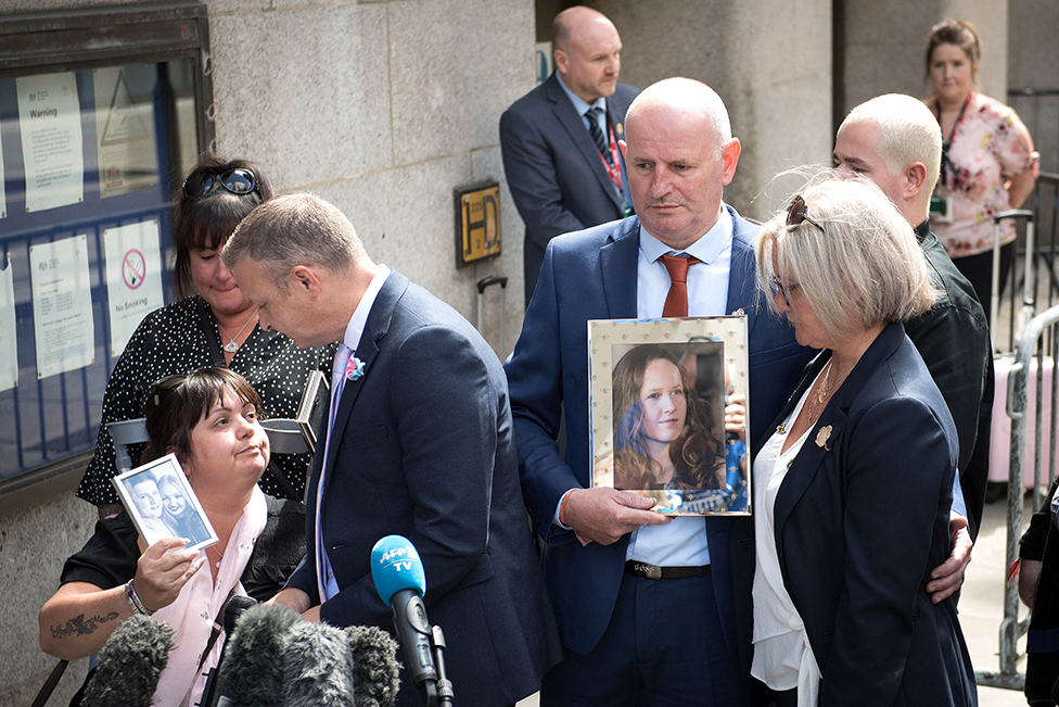Families of victims of the Manchester Arena bombing hold photos outside the Old Bailey