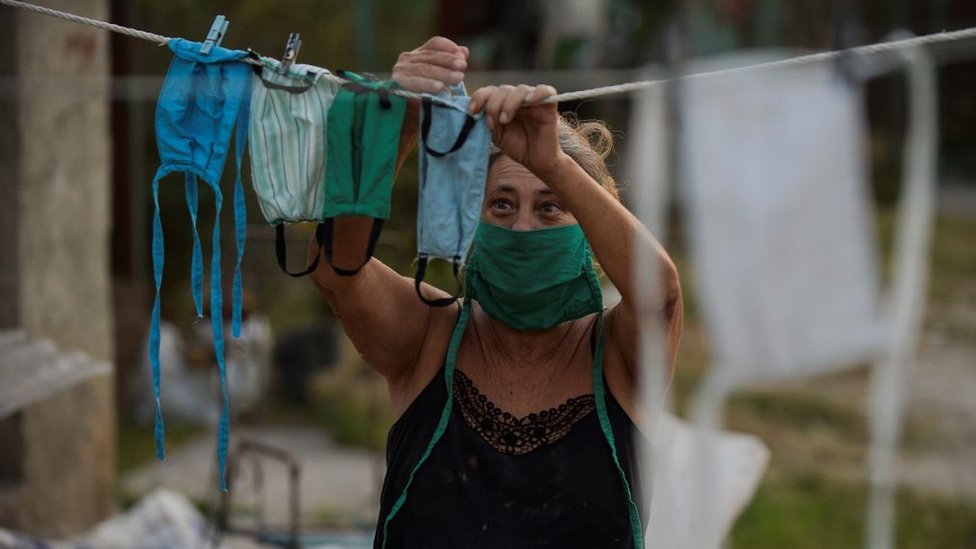Una mujer colgando mascarillas recién lavadas en un cordel.