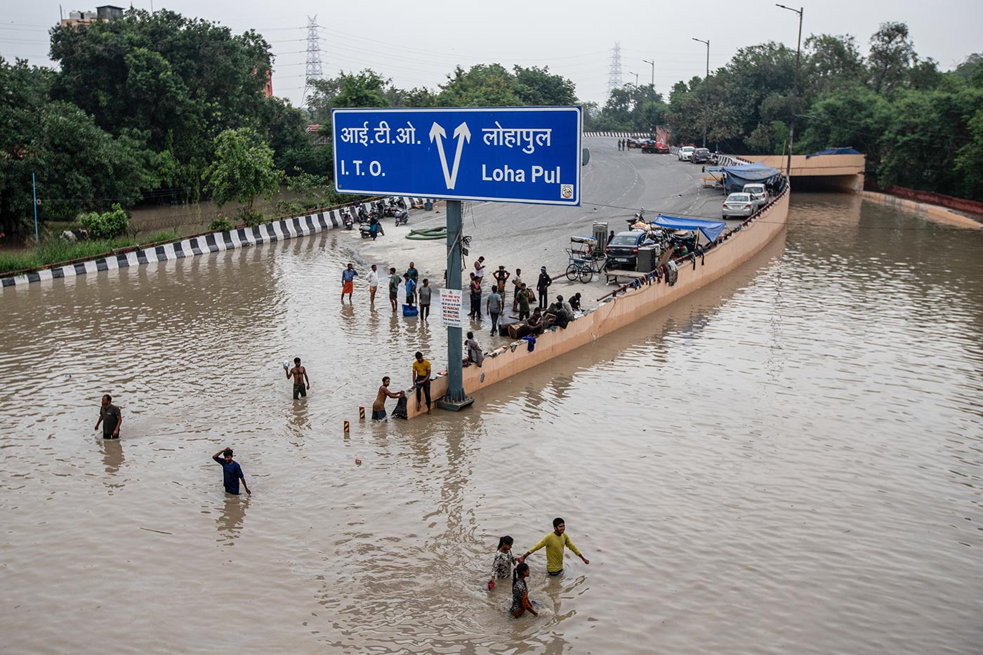 ​​People wade across a flooded road after heavy monsoon rains in New Delhi - 14 July 2023