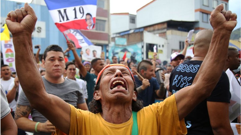 Un hombre festeja el triunfo de Gustavo Petro en las Calles con los brazos hacia arriba y los puños cerrados.