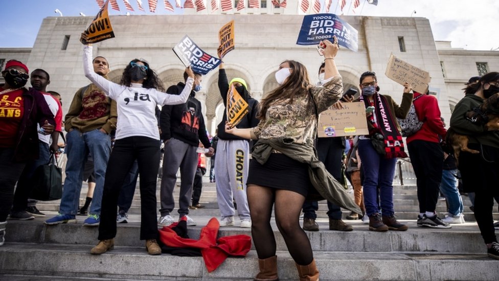 People wave Biden-Harris signs next to Los Angeles City Hall in Downtown Los Angeles, California