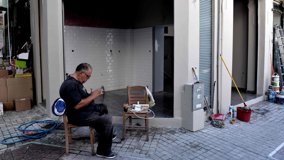 Un hombre sentado frente a su tienda en Thessaloniki