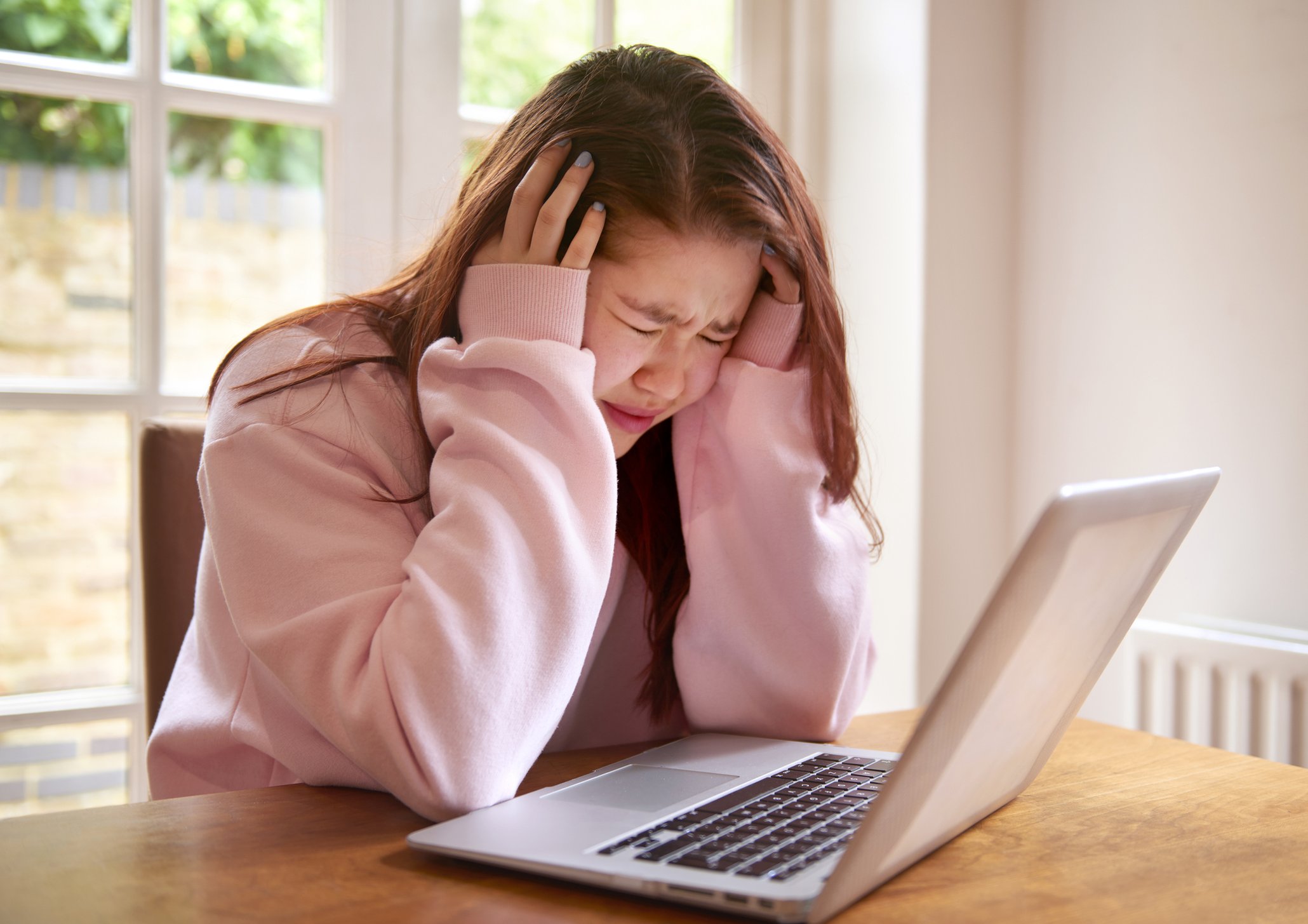 Una mujer llorando mientras ve su computadora