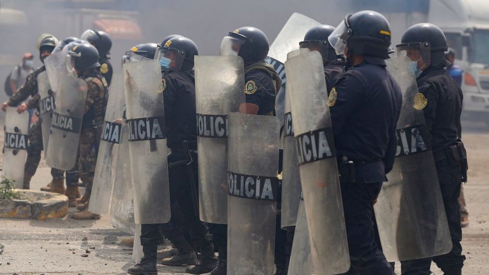Policiais com escudos em frente à manifestação