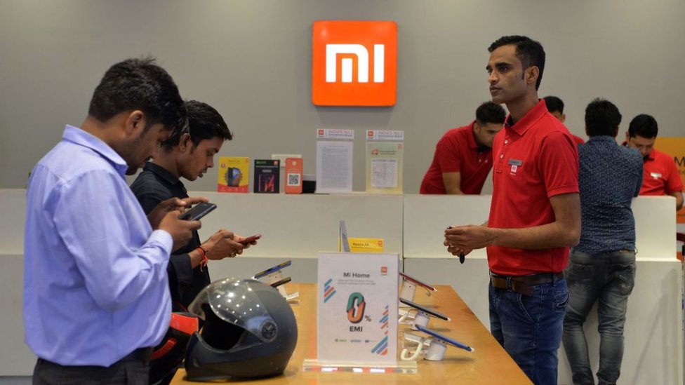 На этой фотографии, сделанной 20 августа 2019 года, покупатели осматривают смартфоны Xiaomi в магазине Mi в Гургаоне.
