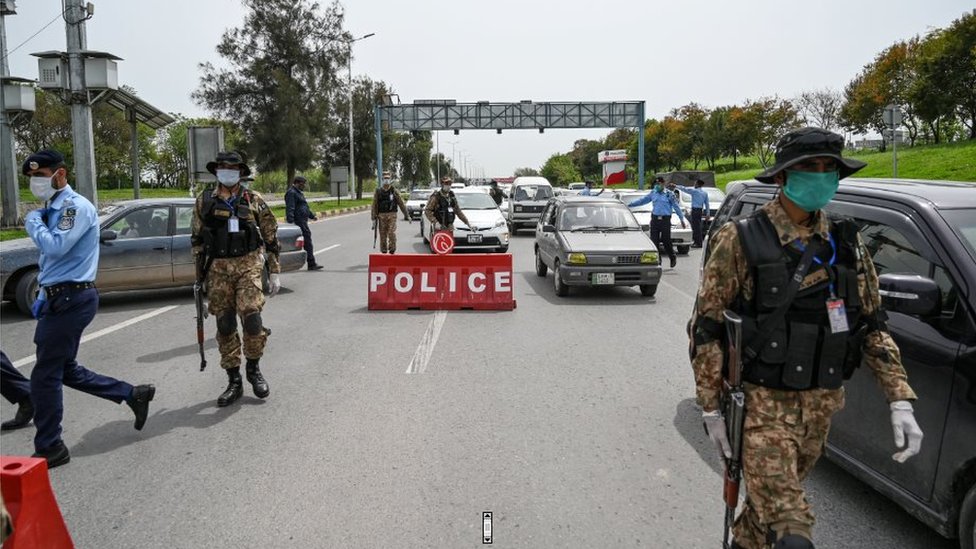 Сотрудники службы безопасности в масках проверяют пассажиров на контрольно-пропускном пункте на въезде в город во время объявленной правительством общенациональной блокировки в качестве превентивной меры против коронавируса COVID-19 в Исламабаде