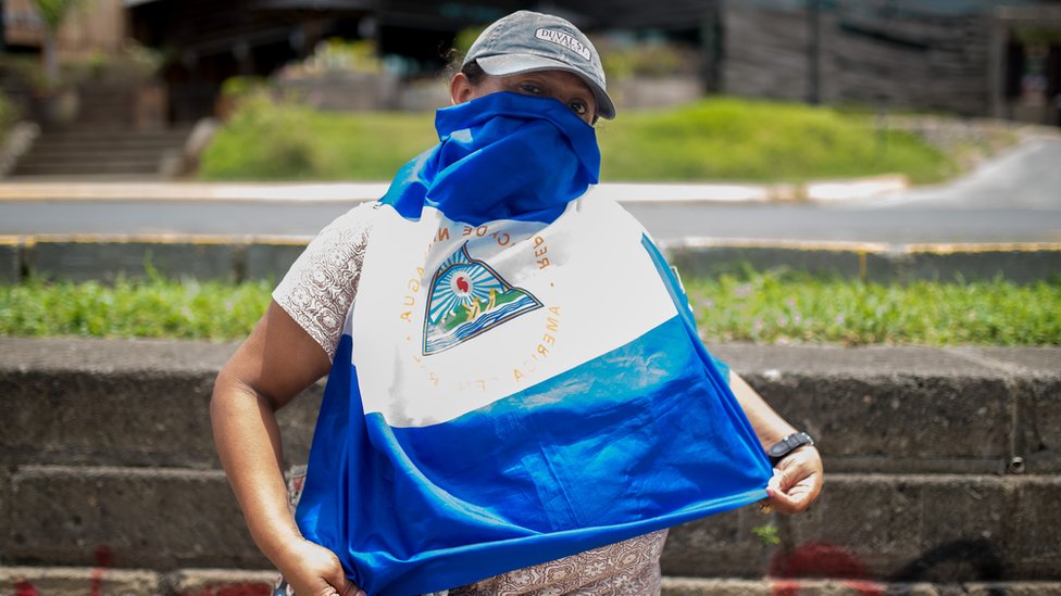 Протестующий в Никарагуа, назвавший Клаудию псевдонимом, закрывает лицо флагом Никарагуа