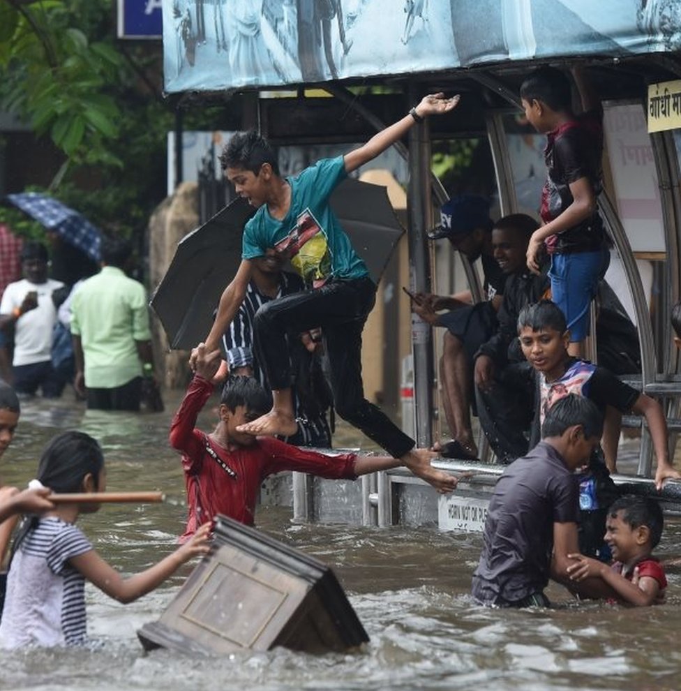 Индийские дети прыгают в воду затопленной улицы после проливного дождя в Мумбаи 1 июля 2019 г.
